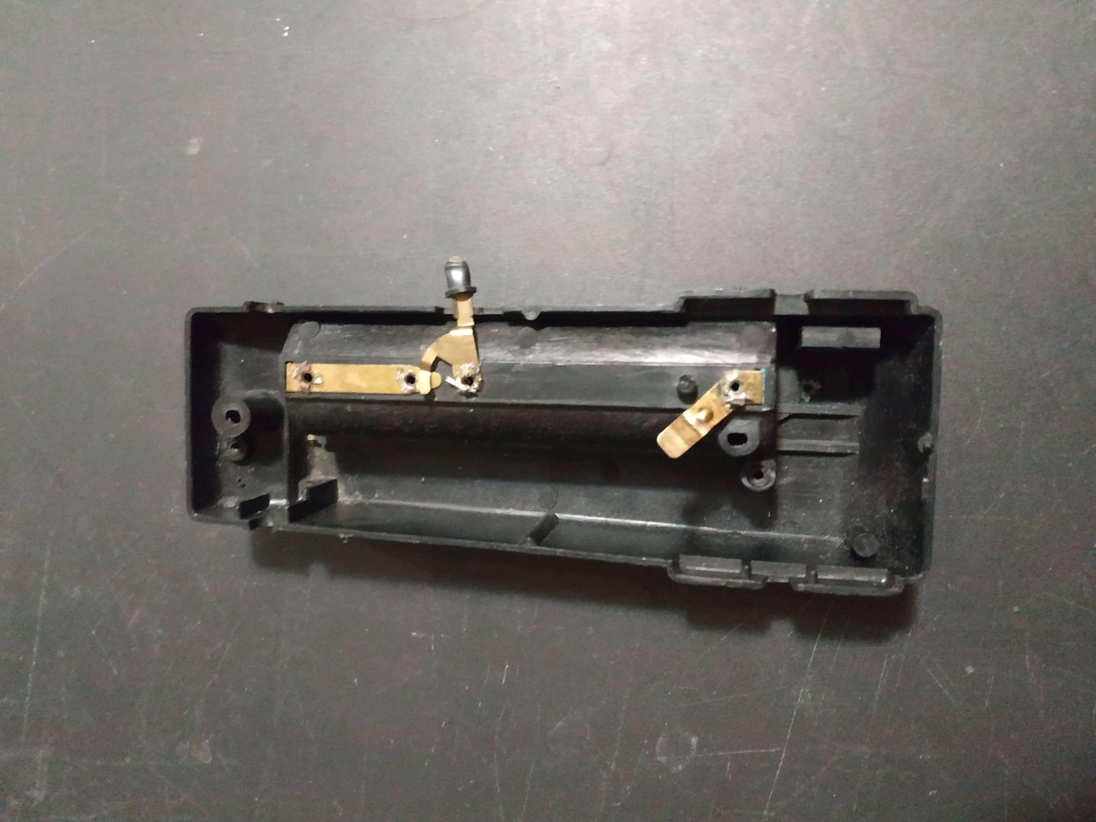 A black plastic part with shiny brass parts connected to it