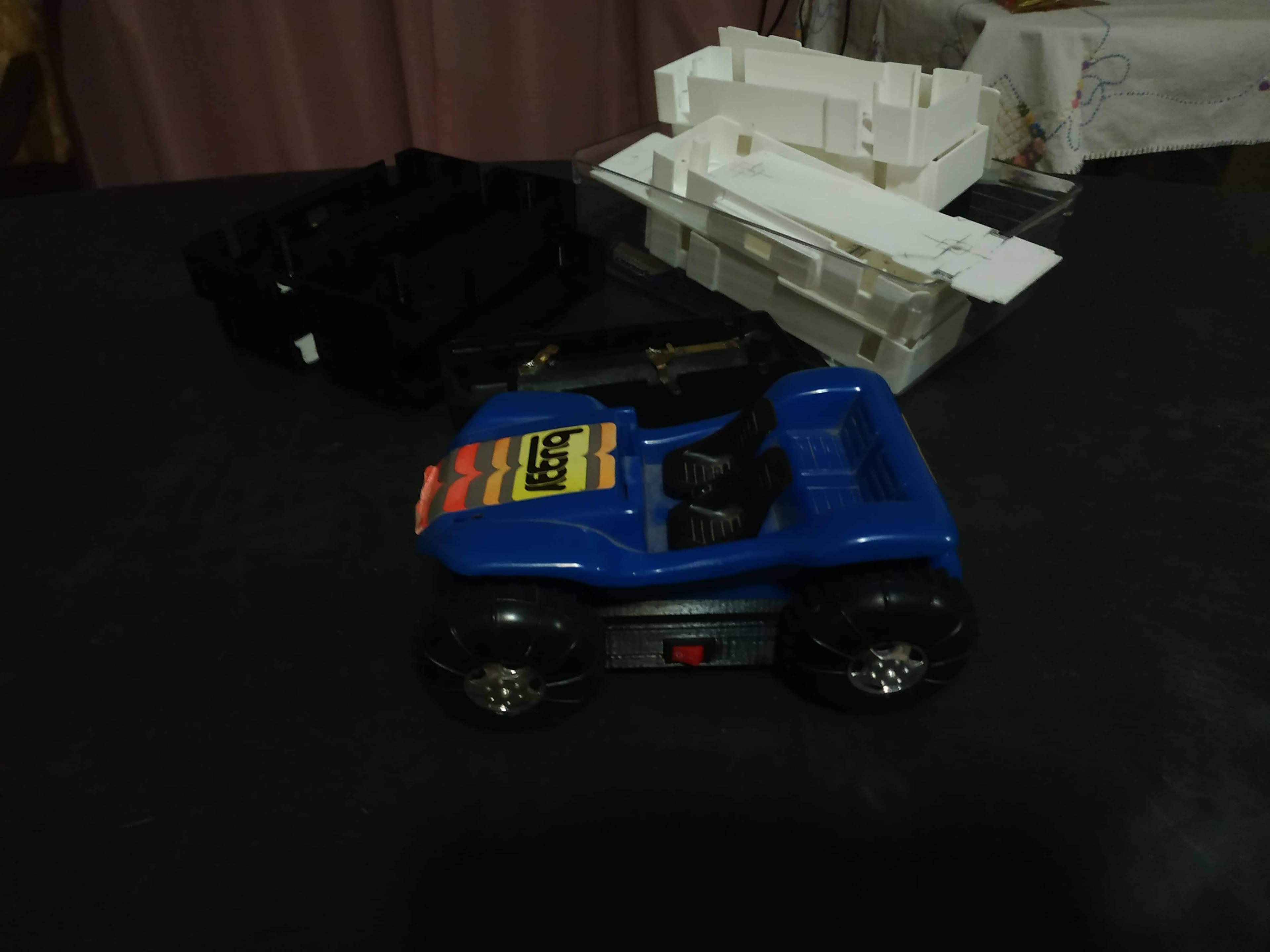 The completed buggy sits on a table in front of a pile of 3D-printed bases and its original base