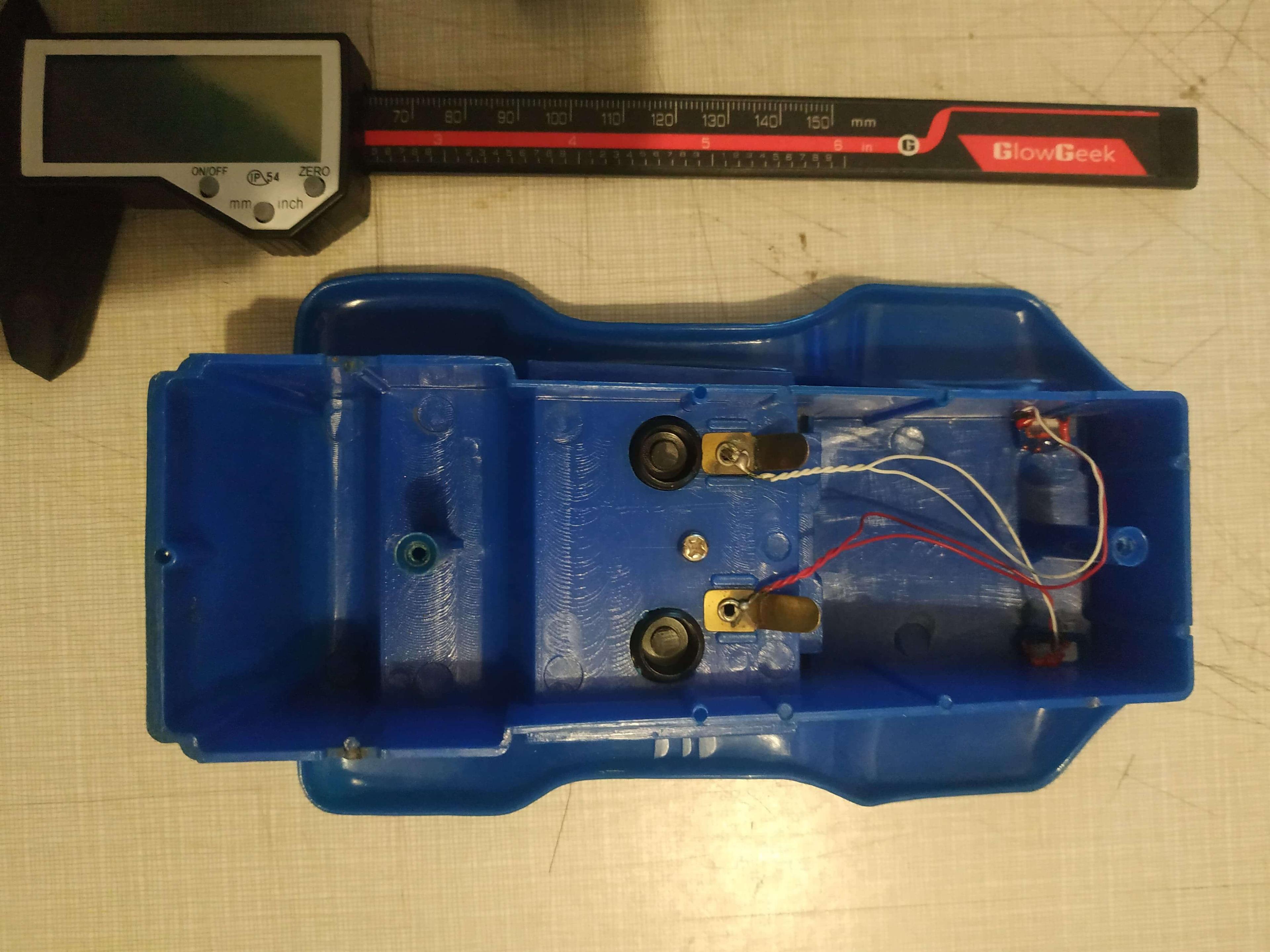 The underside of the blue plastic top of the buggy, with wires going towards lightbulbs at the front, only one of which is still intact