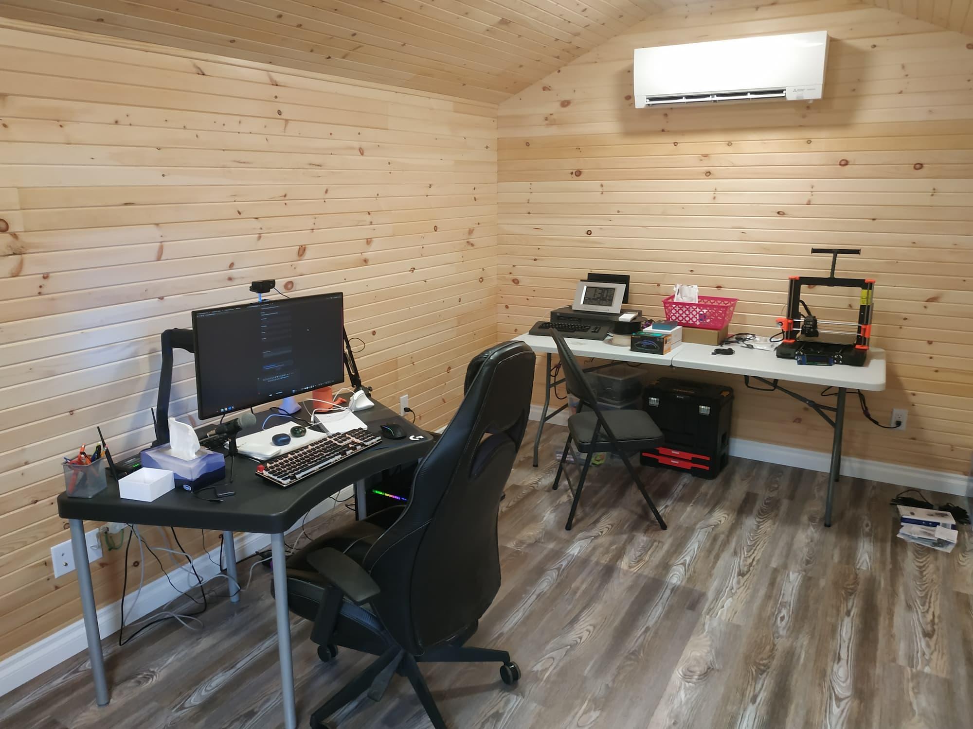 My setup, with the mini-split blower on the north wall, a table with a 3D printer and other things below it. On the west wall closer to the camera, there is a small desk with my computer setup and office chair