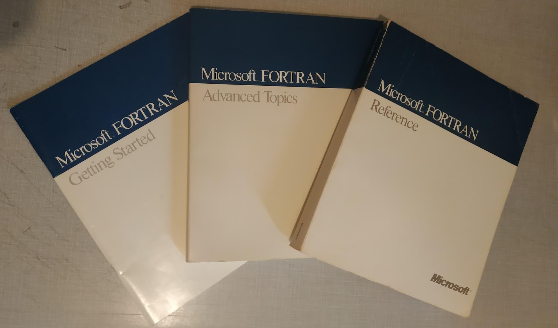 A pamphlet and two larger books on Microsoft FORTRAN are displayed on a table